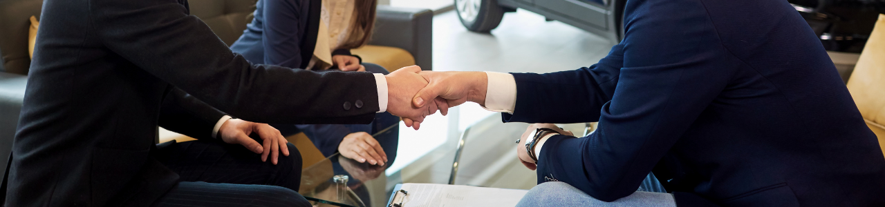 men shaking hands in car dealership